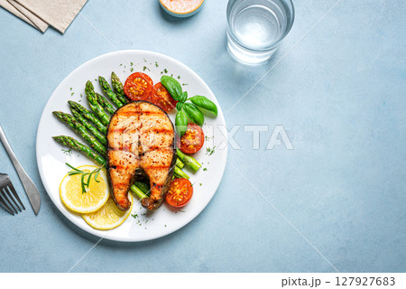 Grilled salmon steak with green asparagus, tomatoes and lemon slices 127927683