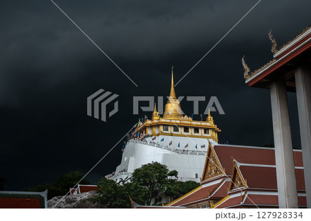 Golden mountain in Wat Saket Bangkok Thailand covered with dark rain clouds at the top looks scary before the rain falls. Golden mountain in Wat Saket Bangkok Thailand covered with dark rain clouds at the top looks scary before the rain falls. 127928334