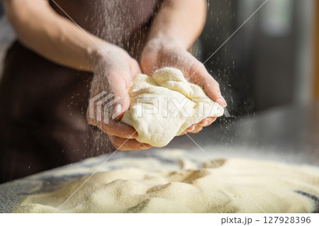 Person kneads dough kitchen pressing firmly preparing pizza base 127928396