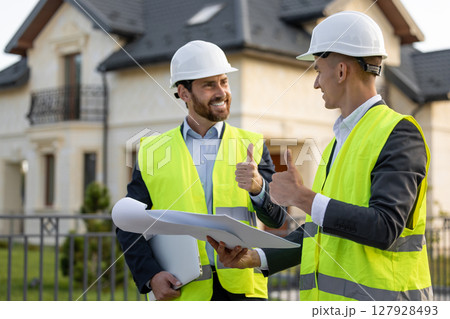 Construction workers reviewing plans in residential area Construction workers reviewing plans in residential area 127928493