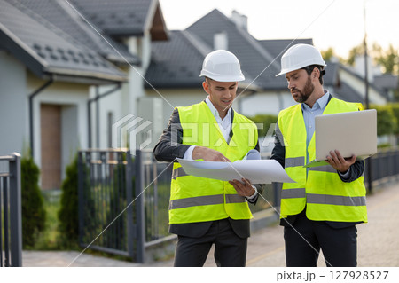 Construction team inspecting site with blueprints Construction team inspecting site with blueprints 127928527