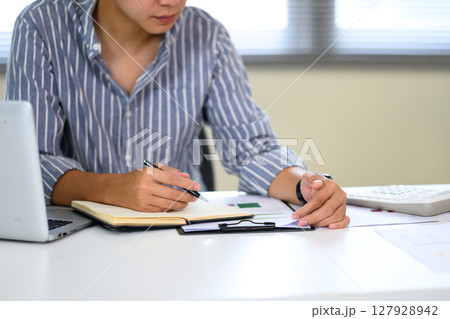 Cropped shot of young accountant working on financial reports at the office Cropped shot of young accountant working on financial reports at the office 127928942