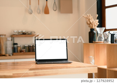 Laptop with blank screen on a wooden kitchen counter. Laptop with blank screen on a wooden kitchen counter. 127928952