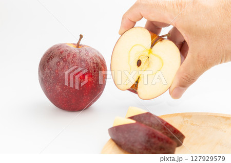 ニュージーランド産の小ぶりなリンゴとカットした林檎を持っている男性の手元の素材写真 127929579