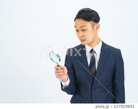 虫眼鏡で何かを見るミドルエイジ男性ビジネスパーソン 虫眼鏡で何かを見るミドルエイジ男性ビジネスパーソン 127929891