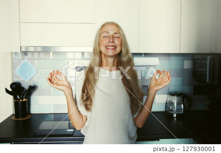 Happy relaxed satisfied woman enjoying at home standing in kitchen Happy relaxed satisfied woman enjoying at home standing in kitchen 127930001