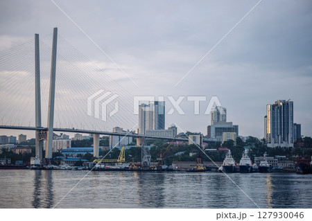 Golden cable stayed bridge crossing zolotoy rog bay, revealing vladivostok's urban landscape with maritime vessels gliding through harbor waters Golden cable stayed bridge crossing zolotoy rog bay, revealing vladivostok's urban landscape with maritime vessels gliding through harbor waters 127930046