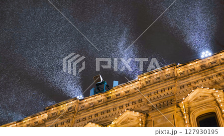 Snow cannon blowing artificial snow over building at night 127930195