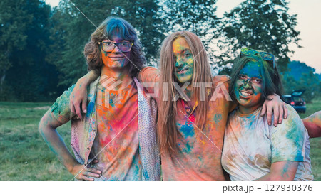 School friends celebrating holi with vibrant powder, embracing each other in colorful festivities 127930376
