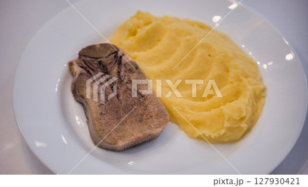 Boiled beef tongue served with mashed potatoes on white plate 127930421