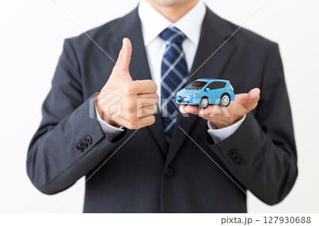 自動車の模型を持ってサムズアップをするスーツを着たミドル男性ビジネスマン 自動車の模型を持ってサムズアップをするスーツを着たミドル男性ビジネスマン 127930688
