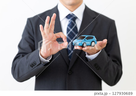 自動車の模型を持って丸サインをするスーツを着たミドル男性ビジネスマン 自動車の模型を持って丸サインをするスーツを着たミドル男性ビジネスマン 127930689