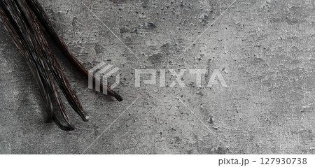 Four bourbon vanilla beans on dark stone like board, view from above, wide banner photo space for text right side 127930738