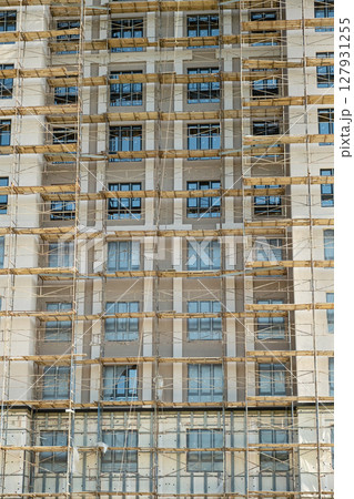 Front Facade of Modern Residential Building Under Construction with Scaffolding. New Apartment Block Development. Front Facade of Modern Residential Building Under Construction with Scaffolding. New Apartment Block Development. 127931255