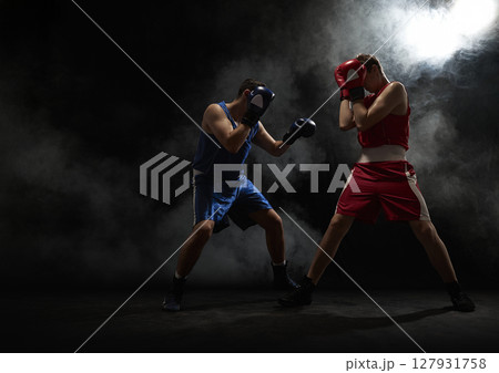 Two boxers sparring in dramatic smoke-filled arena atmosphere 127931758