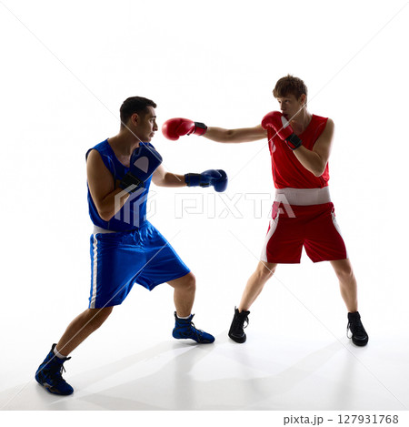 Two boxers sparring in brightly lit studio wearing red and blue sports gear facing each other Two boxers sparring in brightly lit studio wearing red and blue sports gear facing each other 127931768