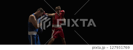 Boxers engaged in intense sparring match with focused expressions against black background 127931769