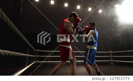 Two boxers facing off in 3D ring under dramatic lighting and smoke effects Two boxers facing off in 3D ring under dramatic lighting and smoke effects 127931773