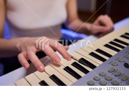 Hands play a keyboard in a modern studio, showcasing creativity and passion for music 127932133