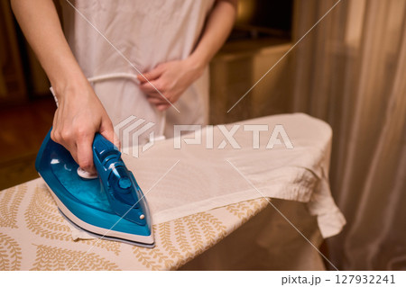 A person meticulously ironing clothes at home, ensuring all garments are neat and well cared for A person meticulously ironing clothes at home, ensuring all garments are neat and well cared for 127932241