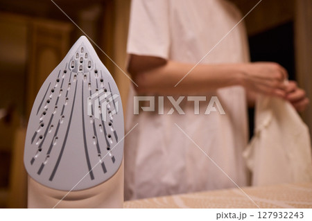A person meticulously ironing clothes at home, ensuring all garments are neat and well cared for A person meticulously ironing clothes at home, ensuring all garments are neat and well cared for 127932243