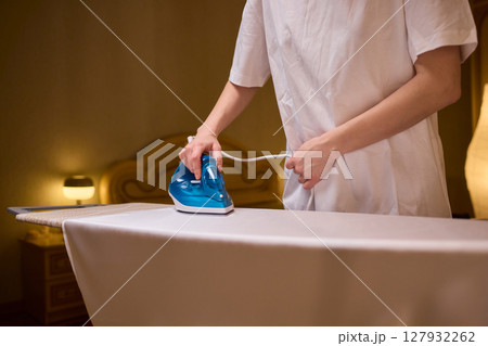 A person meticulously ironing clothes at home, ensuring all garments are neat and well cared for A person meticulously ironing clothes at home, ensuring all garments are neat and well cared for 127932262