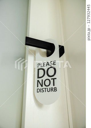 Modern black door handle with a white hanging sign that reads Please Do Not Disturb in bold black letters Modern black door handle with a white hanging sign that reads Please Do Not Disturb in bold black letters 127932445