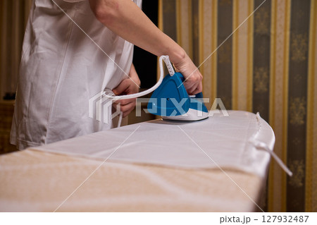 A person meticulously ironing clothes at home, ensuring all garments are neat and well cared for A person meticulously ironing clothes at home, ensuring all garments are neat and well cared for 127932487