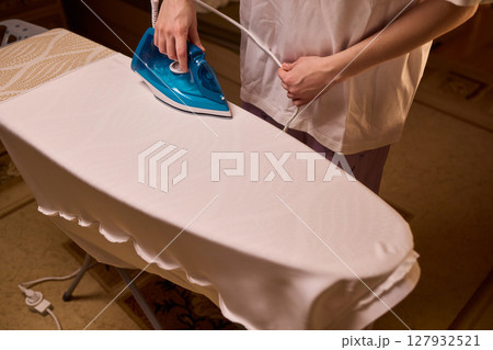 A person meticulously ironing clothes at home, ensuring all garments are neat and well cared for A person meticulously ironing clothes at home, ensuring all garments are neat and well cared for 127932521