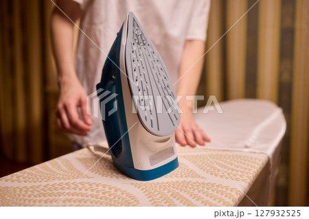 A person meticulously ironing clothes at home, ensuring all garments are neat and well cared for A person meticulously ironing clothes at home, ensuring all garments are neat and well cared for 127932525