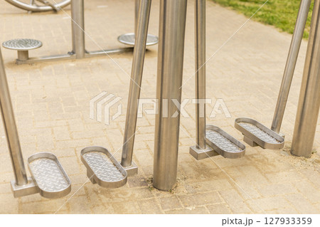 Sturdy metal fitness equipment is positioned in an outdoor park area, showcasing pedals designed for leg exercises, inviting community members to engage in physical activity Sturdy metal fitness equipment is positioned in an outdoor park area, showcasing pedals designed for leg exercises, inviting community members to engage in physical activity 127933359