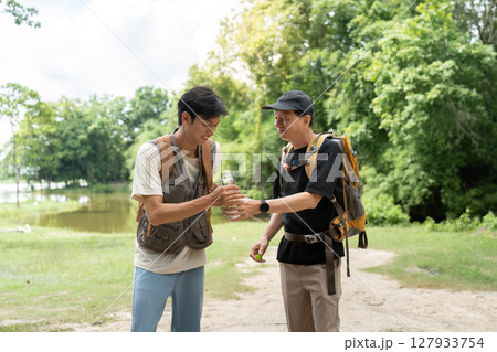 Father and Son Hiking Adventure. Two men enjoying nature while exploring a scenic trail. Father and Son Hiking Adventure. Two men enjoying nature while exploring a scenic trail. 127933754