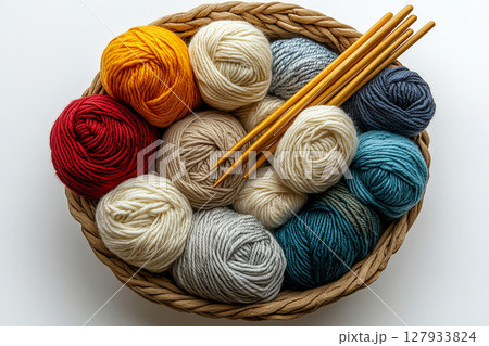 Playful Textures.  Vibrant yarn skeins and knitting needles in a wicker basket on a white background. 127933824