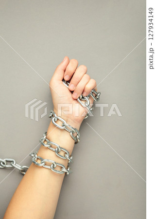 Hands are chained in chains on grey background. Vertical photo 127934149