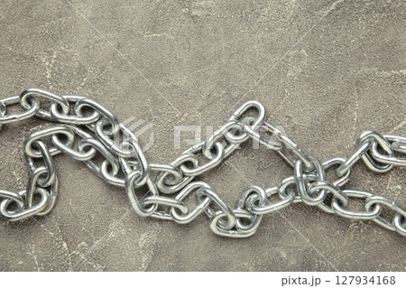 Iron chain of light metal on grey concrete background. Iron chain of light metal on grey concrete background. 127934168