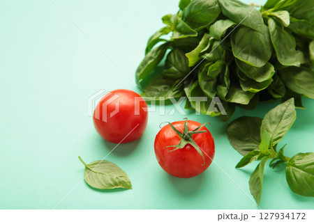 Cherry tomatoes and green basil on mint background Cherry tomatoes and green basil on mint background 127934172