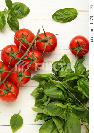 Cherry tomatoes and green basil on white background. Vertical photo Cherry tomatoes and green basil on white background. Vertical photo 127934173