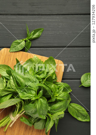Green basil herb on cutting board on black background. Vertical photo 127934206