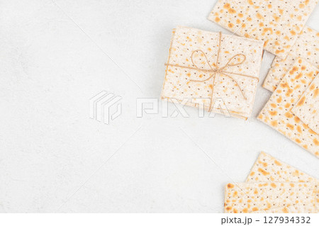 Matzo crackers neatly tied with string rest on a light textured surface, symbolizing Jewish tradition, simplicity, and the observance of Shabbat and Passover Matzo crackers neatly tied with string rest on a light textured surface, symbolizing Jewish tradition, simplicity, and the observance of Shabbat and Passover 127934332