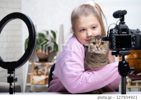 A beautiful blonde -teenage broadcasts live with her cat. Living a broadcast. Ring lamp and camera during a direct broadcast of a video -blogger A beautiful blonde -teenage broadcasts live with her cat. Living a broadcast. Ring lamp and camera during a direct broadcast of a video -blogger 127934921