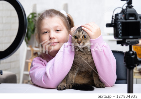 A beautiful blonde -teenage broadcasts live with her cat. Living a broadcast. Ring lamp and camera during a direct broadcast of a video -blogger A beautiful blonde -teenage broadcasts live with her cat. Living a broadcast. Ring lamp and camera during a direct broadcast of a video -blogger 127934935