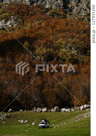 White camper van parked on a green meadow at the edge of colorful autumn forest below the mountains in Prokletije, Montenegro. Vanlife outdoor travel concept White camper van parked on a green meadow at the edge of colorful autumn forest below the mountains in Prokletije, Montenegro. Vanlife outdoor travel concept 127935200