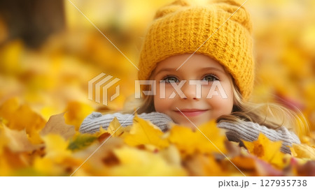 Adorable Young Girl in Yellow Knit Hat Smiling Among Autumn Leaves 127935738