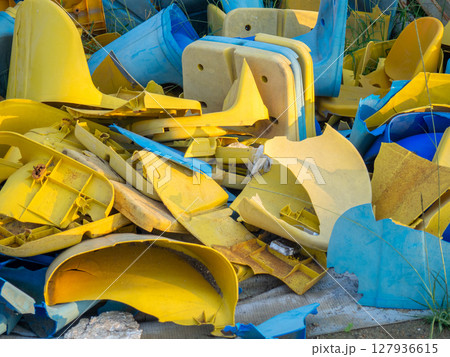 Old broken plastic chairs at the stadium. Fan riot concept. A pile of plastic chairs. 127936615