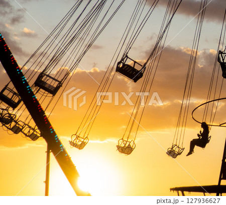 Silhouettes of people on the carousel. Concept of fun and entertainment. People on carousels at sunset. Resort town. Lunapark.  Speed carousel 127936627