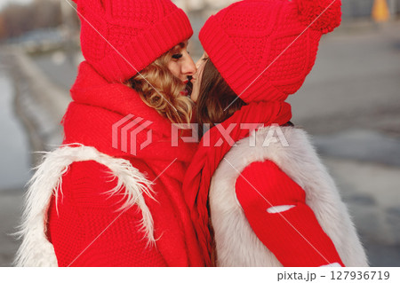 Mother and child in knitted winter hats on family Christmas vacation. Handmade wool hat and scarf for mom and kid. Knitting for kids. Knit outerwear. Woman and little girl in a park. Mother and child in knitted winter hats on family Christmas vacation. Handmade wool hat and scarf for mom and kid. Knitting for kids. Knit outerwear. Woman and little girl in a park. 127936719