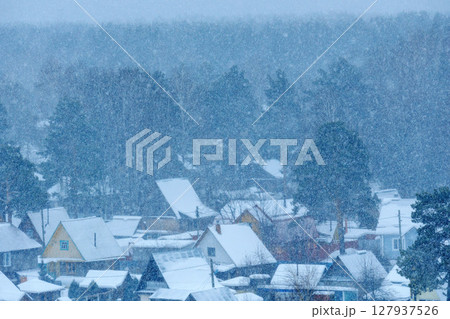 Snowfall blankets a quiet village in the winter season, creating a serene atmosphere and enchanting landscape 127937526
