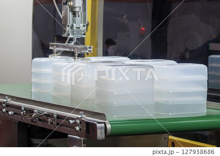 Close up scene material handling process the food container by robotic system from injection machine. 127938686