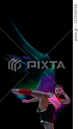 Fierce kickboxer girl in midair kick with vivid neon stream. Fitness and athletic 127939358