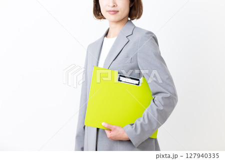 ファイルを抱えて微笑むスーツ姿のミドル女性 127940335